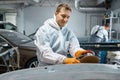 Serviceman polishing car body part in workshop