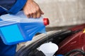 Serviceman Pouring Windshield Washer Fluid Into Car