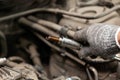 A serviceman repairs a car while replacing the spark plugs while holding one of them in hand with a glove while unscrewing them Royalty Free Stock Photo