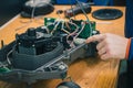 Serviceman replacing water seals on robotic lawnmower, motorized lawnmower being serviced on a table after a year of use in the
