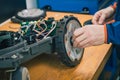 Serviceman replacing wheels on robotic lawnmower, motorized lawnmower being serviced on a table after a year of use in the mud