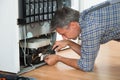 Serviceman Working On Fridge At Home