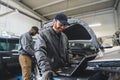 Servicemen completing car engine diagnostics with laptop in a repair shop Royalty Free Stock Photo