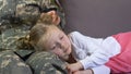 Servicewoman stroking sleeping daughter relaxing on sofa, family connection