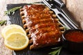 Serving BBQ pork ribs with chili sauce and lemon close up on a slate board. horizontal