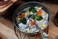 Serving bowl of fresh salty herring with red caviar, onion and green on stand closeup top view. Portion of seasonal