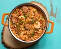 Overhead view of an orange enamel cast iron pot filled with Cajun etouffee on a turquoise table.