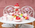 Serving festive table of appetizing cakes, sweet desserts, fresh strawberry and raspberry, tasty drinks. Party in pink