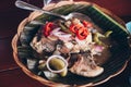 Serving of Filipino dish Tilapia fish simmered in vinegar and spices on banana leaf on rattan wooden plate