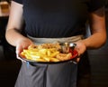 A Serving of french fries and deep fried snack with tomato sauce served by waiter in a plate.