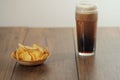 Serving of fresh crisps in wooden small bowl and a pint glass with dark stout beer with white foam on top on a dark wood table Royalty Free Stock Photo