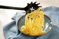 Serving fresh pasta, spaghetti are filled onto a blue plate with a special spoon, napkin on a light table, copy space, selected Royalty Free Stock Photo