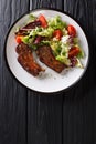 Serving fried lamb ribs with fresh vegetable salad close-up on a plate. Vertical top view Royalty Free Stock Photo