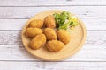 Serving of ham croquettes on a round wooden plate