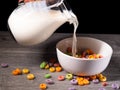 Serving milk in a white bowl with colorful sugary cereal Royalty Free Stock Photo