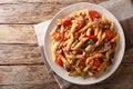 Serving penne pasta with pulled pork, cheese, tomato sauce and herbs close-up on a plate. horizontal top view