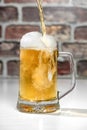 Serving a refreshing beer mug with foam on a white bar Royalty Free Stock Photo