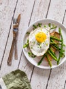 A serving of roasted salmon with sauteed asparagus and a fried egg on top.