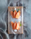 A serving of salmon sits on a wooden tableware, surrounded by a white mist of water.