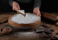 Serving a slice of cake on a cake server by womans hand on rustic, wooden and rural table background