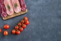 Serving of the slices of smoked sausages lie on a cutting board in several rows on a wooden stand.