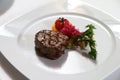 Serving a steak on a white plate with tomato, vegetables garnish. Fancy dinner main course, steak with grill marks