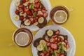 Serving for two.Top view. Fresh pancakes with chopped fruits, strawberries, bananas, kiwi and honey on light plates. Two cups of