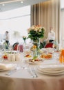 Serving the wedding table. Restaurant business. Glasses, white plates and cutlery on a round table decorated with roses in a white Royalty Free Stock Photo