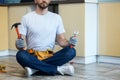 Serving you. Cropped shot of young handyman holding a hammer and an adjustable wrench in his hands while sitting on the Royalty Free Stock Photo