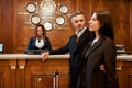 Serving your need. Happy couple checking in hotel at reception desk. Man and woman with a suitcase waiting for female Royalty Free Stock Photo