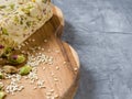 Sesame halva with pistachios on a teak chopping board on a grey background.