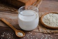 Sesame milk in glass and white sesame seeds on wooden spoon