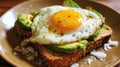 Sesame seed toast with creamy avocado and a sunny side up egg, sprinkled with coconut flakes and red pepper, on a golden plate