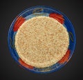 Sesame seeds in a blue glass bowl. Top view of white sesame seeds in a round bowl on a black background Royalty Free Stock Photo