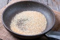 Sesame seeds are fried in the pan on a wooden table