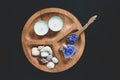 Seshels, bottle, lavender salts and spoon, white candle on the wooden round form. Black background