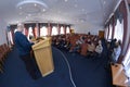 Session of regional council. Deputies sitting in a hall, speaker keeping speach at the tribune, head and his assistants sitting at