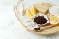 Set for anti-cellulite massage procedures. Coffee scrub, coffee grains, lemon, soap, sponge on wooden plate and gray background,