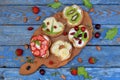 Set of assorted healthy wholewheat bread sandwiches with fruit, cheese and leafy green herbs on picnic wooden table