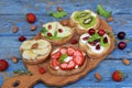 Set of assorted healthy wholewheat bread sandwiches with fruit, cheese and leafy green herbs on picnic wooden table