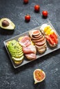 A set of avocado sandwiches, cherry tomatoes and eggs, figs, prochutto on a stone background. Royalty Free Stock Photo