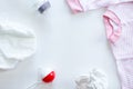 Set of baby supplies on table: diaper, beanbag, bottle, suit