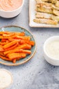 Set of baked season vegetable sticks of zucchini and carrots with sauce and hummus