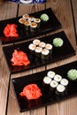 Set of baked sushi rolls with wasabi and ginger on a black background