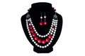 Set of beaded red and white necklace and earrings on black velvet bust isolated on white background. Female accessories Royalty Free Stock Photo