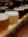 set of Beer samplers in small glasses individually placed in holes into a unique wooden tray and background. Royalty Free Stock Photo