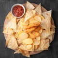 Set of beer snacks. Composed of nachos chips, french fries and nuggets. With tomato sauce. Served on a round wooden board. View Royalty Free Stock Photo