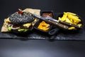 Set of the black burger. Stone plate with: black burger roll slices of juicy marble beef, fused cheese, fresh salad with French fr Royalty Free Stock Photo