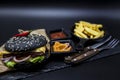 Set of the black burger. Stone plate with: black burger roll slices of juicy marble beef, fused cheese, fresh salad with French fr Royalty Free Stock Photo