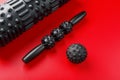 Set of Black lumpy foam massage roller, body roller, rubber ball on red background Royalty Free Stock Photo